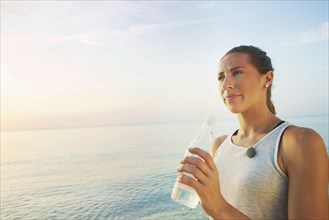 Athlete drinking water bottle on beach
