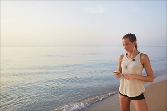 Athlete listening to earphones on beach