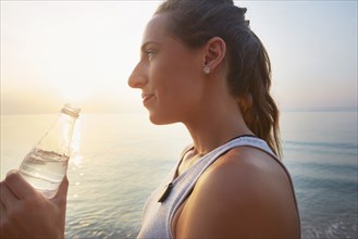 Athlete drinking water bottle on beach