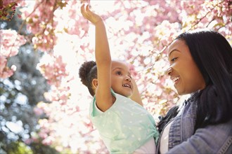 Mother and daughter under flowering tree in park