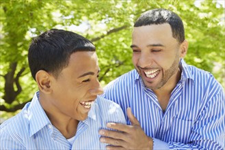 Hispanic father and son laughing in park