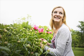 Caucasian woman smelling flowers in park
