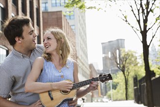 Caucasian couple playing ukulele in city