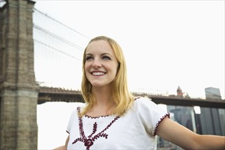 Caucasian woman smiling under Brooklyn Bridge