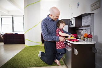 Father and daughter playing in toy kitchen
