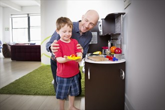 Father and son playing in toy kitchen