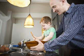Father teaching son to cook in kitchen