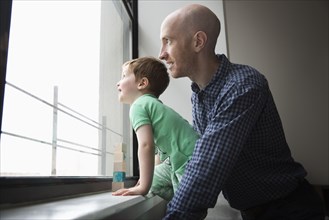 Father and son looking out window