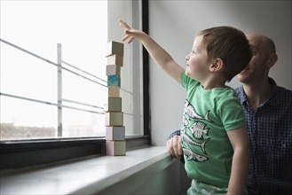 Father and son stacking blocks in window
