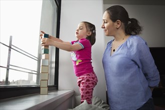 Mother and daughter stacking blocks in window