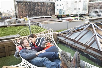 Couple laying in hammock on urban rooftop