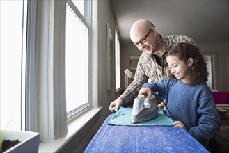 Father teaching daughter to iron fabric