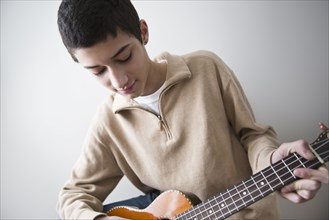 Mixed race teenage boy playing guitar