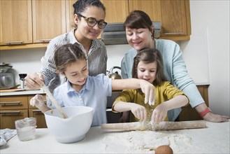 Mothers teaching daughters to bake in kitchen