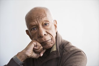 Older Black man resting chin in hand