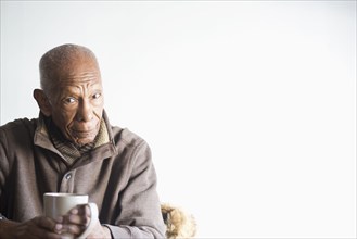 Older Black man drinking cup of coffee