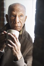 Older Black man drinking cup of coffee