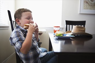 Caucasian boy eating sandwich at table