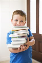 Caucasian boy carrying stack of books