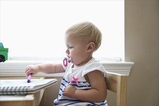 Caucasian baby girl drawing with crayon