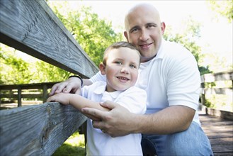 Caucasian father posing with son on wooden footbridge