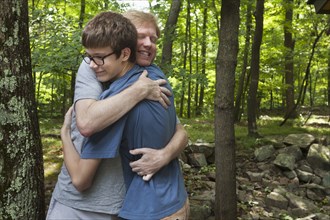 Caucasian father and son hugging in forest
