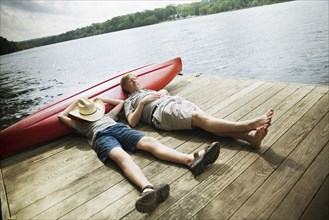 Caucasian father and son laying on wooden dock