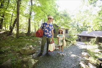 Caucasian father and daughter carrying bags at cabin