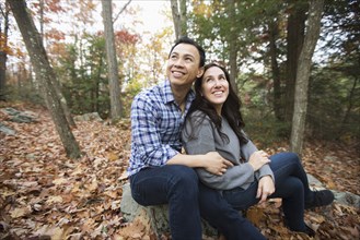 Couple sitting on rock in forest during autumn
