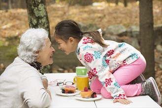 Grandmother and granddaughter playing at breakfast table outdoors