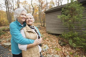 Caucasian women hugging outdoors near cabin