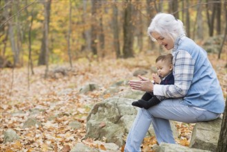 Grandmother playing with baby grandson in autumn
