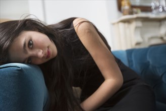Pensive Caucasian girl resting head on armchair