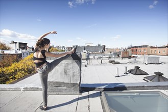 Caucasian girl stretching leg on rooftop
