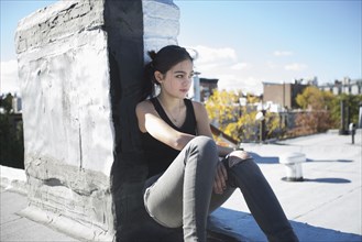 Caucasian girl sitting on rooftop