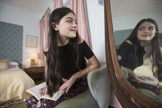 Caucasian girl reading book smiling in mirror