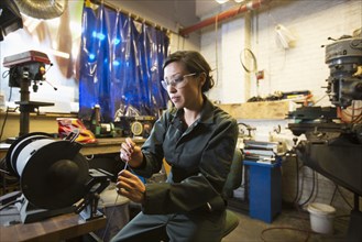 Mixed Race woman holding metal rod in workshop