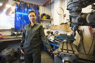 Mixed Race woman posing near machinery in workshop