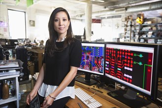 Mixed Race woman posing near circuits on computer monitors