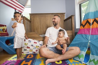 Father watching son waving American flag in playroom