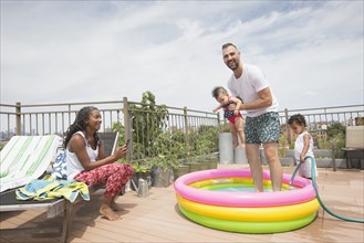 Parents playing with children in inflatable swimming pool
