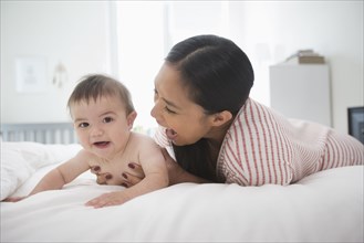 Mother playing on bed with baby son