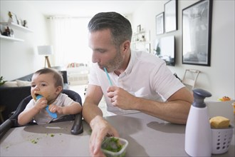 Father watching baby son eating