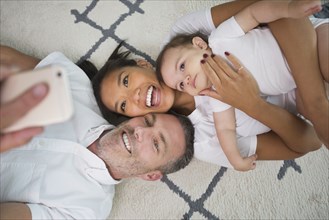 Family laying on floor posing for cell phone selfie