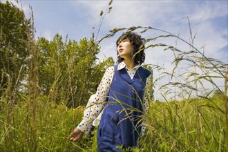 Asian woman walking through tall grass