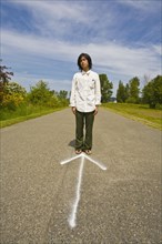 Asian man standing on arrow in road