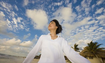 Asian woman walking under blue sky with clouds