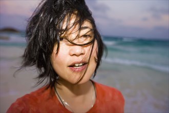 Asian woman with hair blowing at beach