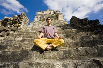 Asian woman meditating on temple ruins