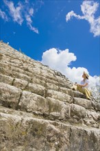 Asian woman sitting on Mayan temple steps